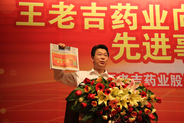 倪依东同志举起刊登着红罐与绿盒王老吉祝贺神九发射成功这则消息的